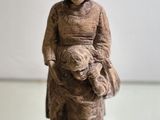 a statue of a woman holding a baby on a wooden block