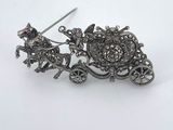 an image of a silver brooch with a horse and carriage on it