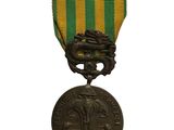 une vieille médaille en bronze ornée d'un ruban vert, jaune et rouge