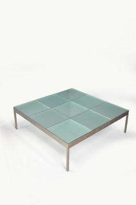 une table basse en verre avec des pieds en métal et un plateau carré en verre