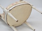a small wooden chair with a large drum on it ' s legs