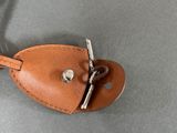 brown leather key foble with a metal clasp on a gray surface