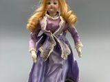 porcelain doll of a woman in a purple dress with a white lace trim