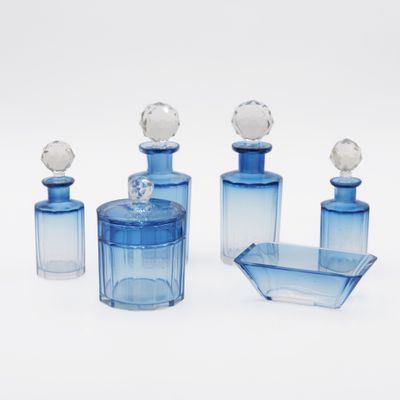 three blue glass bottles and a tray on a white surface