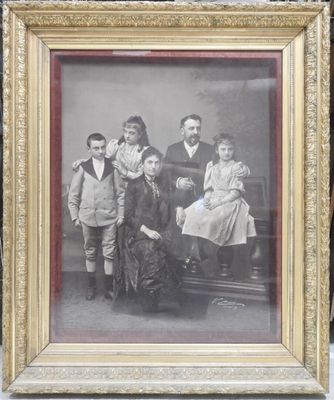 une vieille photo d'une famille posant pour une photo, dans un cadre doré