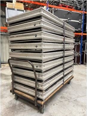 une grande pile de plateaux métalliques posée sur une palette dans un entrepôt