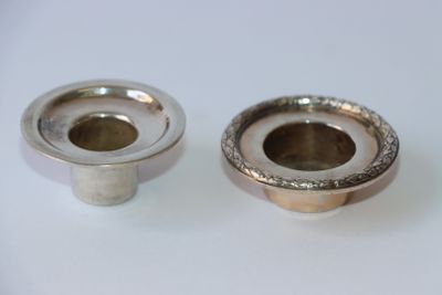 deux bougeoirs en argent posés sur une table blanche