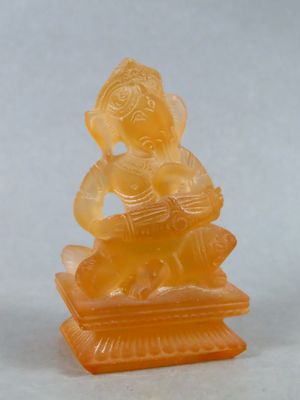 une statue en jade orange représentant un homme assis sur un rocher