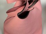 pink handbag with black handles on a white surface