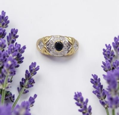 un gros plan d'une bague ornée d'une pierre noire entourée de fleurs violettes