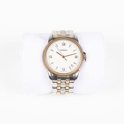 une montre en argent et en or posée sur une serviette blanche