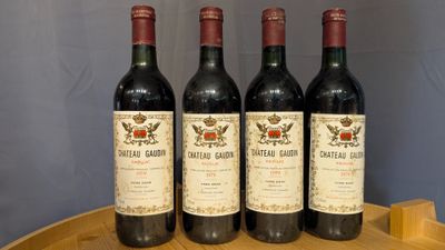 four bottles of red wine are lined up on a wooden tray