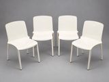 four white plastic chairs sit in a circle on a gray surface