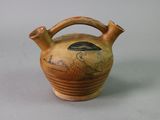 a brown vase with a bird on it on a table