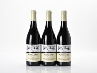trois bouteilles de vin rouge sont posées sur une surface blanche