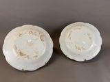 two white plates with brown spots on them sitting on a table