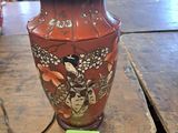 un vase rouge posé sur une table en bois, sur laquelle est accrochée une étiquette verte