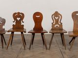 six chaises en bois sont alignées en rangée contre un mur blanc