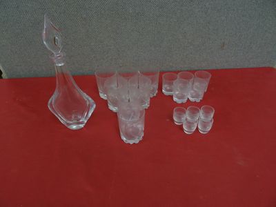a lot of glasses and a decanter on a red table