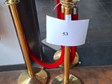 a red carpet and a gold pole with a sign on it