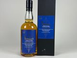 une bouteille de whisky posée à côté d'une boîte sur une surface blanche