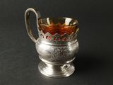 une coupe ancienne en argent, munie d'une anse et d'une poignée, sur un fond noir