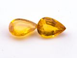 two yellow sapphires on a white surface with a white background