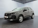 Une voiture grise est garée dans une grande pièce aux murs blancs.