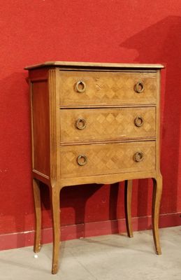 une petite commode exposée devant un mur rouge