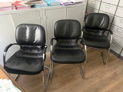 three black leather office chairs sitting in a room