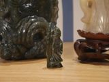 a statue of a monkey sitting on a table next to a vase