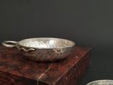 a silver bowl sitting on top of a box next to a silver bowl
