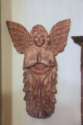 a statue of an angel on the wall next to a clock