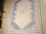 an image of a rug on the floor with a chair in the background