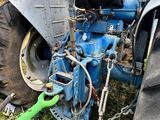 un tracteur bleu auquel est raccordé un tuyau vert
