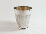 a silver cup that is sitting on a white surface