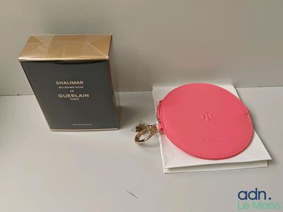 Le petit sac à main rose se trouve à côté d'une boîte et d'un porte-clés