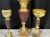 trois vases dorés posés sur une table blanche, sur fond noir