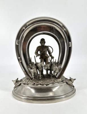 une figurine en argent représentant un homme avec un chien dans un fer à cheval