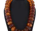 un collier composé de perles d'ambre de la Baltique, présenté sur un mannequin noir