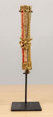 un objet doré et rouge posé sur un socle, sur une table en bois