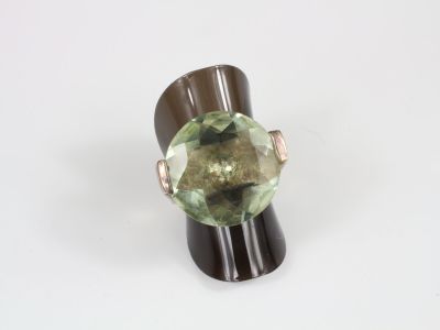 an image of a ring with a green stone on top of a wooden stand