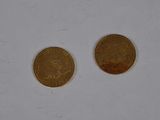 two coins sitting on top of a white surface next to each other