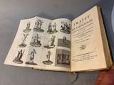 someone is holding an open book with pictures of figures on it