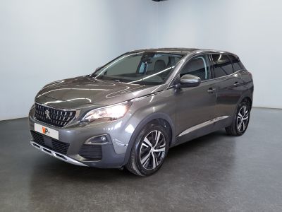 La voiture grise est garée dans une grande pièce au sol noir.