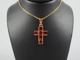 un collier avec une croix dorée et rouge autour du cou d'un mannequin