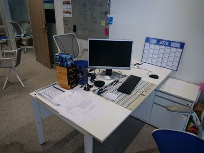 un bureau sur lequel se trouvent un ordinateur, un clavier, une souris et un agenda