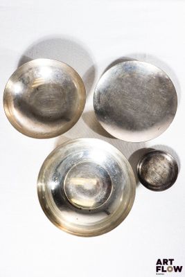 trois bols en argent et un bol en argent posés sur une surface blanche