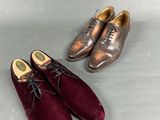 two pairs of men ' s shoes are lined up on a table