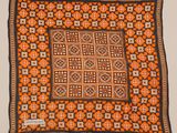 un tapis carré orange, noir et blanc, orné d'un motif